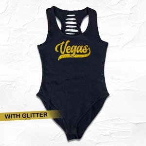 May include: Black sleeveless bodysuit with a gold glitter "Vegas" graphic.