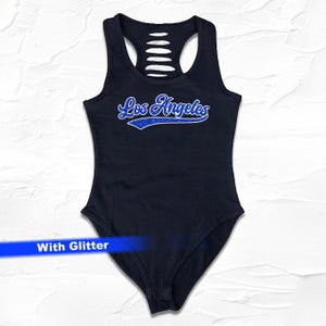 May include: Black bodysuit with a blue glitter "Los Angeles" graphic on the front. The bodysuit has a cutout design on the back.