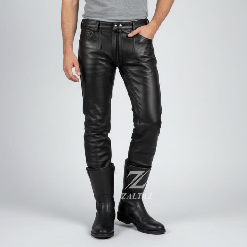 K&ouml;nnte beinhalten: Schwarze Lederhose mit Rei&szlig;verschluss und Taschen. Die Hose wird mit schwarzen Lederstiefeln getragen. Die Stiefel haben einen seitlichen Rei&szlig;verschluss und ein Logo auf der Seite. Die Hose hat ein klassisches, figurbetontes Design.