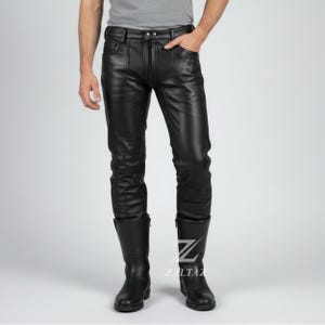 K&ouml;nnte beinhalten: Schwarze Lederhose mit Rei&szlig;verschluss und Taschen. Die Hose wird mit schwarzen Lederstiefeln getragen. Das Bild zeigt eine Person, die die Hose und die Stiefel tr&auml;gt. Die Hose hat ein klassisches, figurbetontes Design.