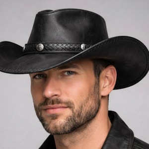 May include: Black leather cowboy hat with a wide brim and a decorative band featuring silver-toned studs. The hat has a classic western design, suitable for outdoor activities or fashion.