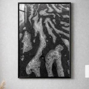 Könnte beinhalten: Schwarz-Weiß-Kunstdruck in einem schwarzen Rahmen. Das Kunstwerk zeigt ein strukturiertes Muster aus organischen Formen, das an fließendes Wasser oder Schaum erinnert. Der Druck hängt über einem beigen Sofa mit Kissen.