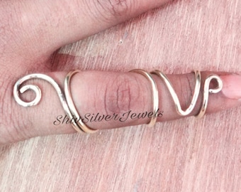 May include: A silver, spiral-shaped ring for the thumb. The ring is made of thin wire and has a simple, modern design.