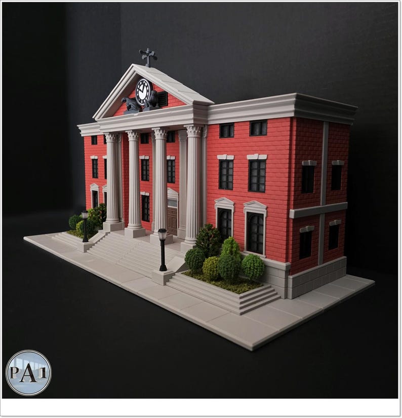 May include: A miniature model of a red brick courthouse with white columns, a clock tower, and a cross on top. The model has a gray base with small green bushes and a black background. The courthouse has multiple windows and a front door.