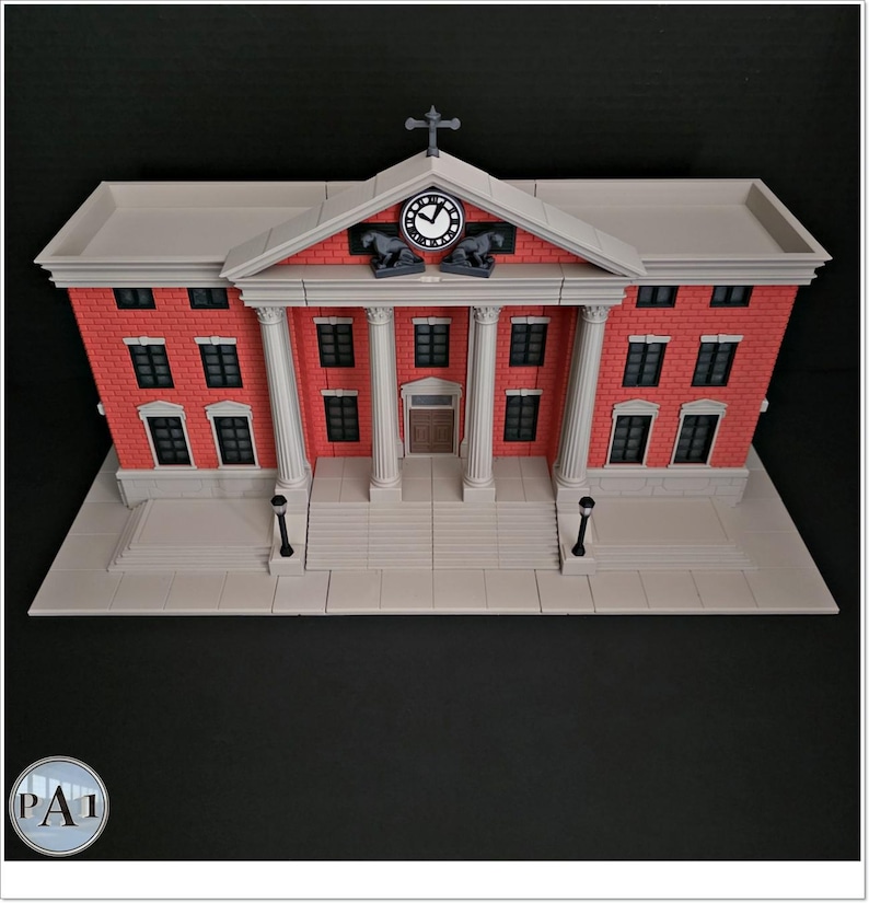 May include: A detailed model of a brick building with white columns, a clock, and a cross on top. The building has multiple windows and a light gray base. The model is a replica of a courthouse.