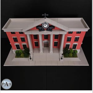 May include: A detailed model of a red brick building with white columns, a clock, and a cross on top. The building has multiple windows and a gray roof. The model includes a base with greenery and street lamps.