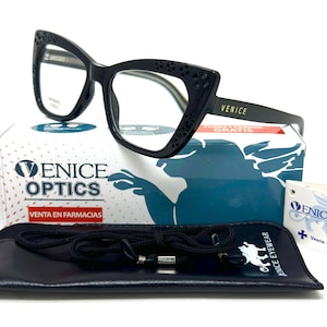 Puede incluir: Gafas negras de ojo de gato con detalles decorativos en el marco. Las gafas se muestran en una caja con el texto "Venice Optics" y "Venta en Farmacias".