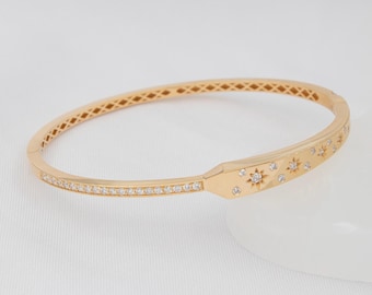 Puede incluir: Un brazalete de oro con una banda engastada con diamantes y un diseño de estrella en la parte delantera.