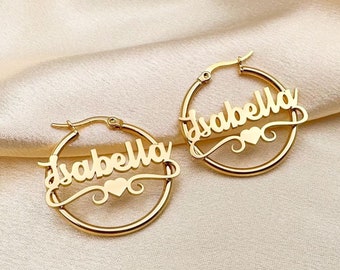 May include: A pair of gold hoop earrings with the name "Isabella" and a small heart charm on each earring.