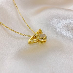 May include: A gold chain necklace with a pendant featuring a delicate angel wing design with a white gemstone in the center.