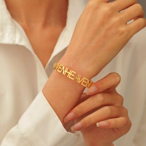 May include: Gold bracelet with the word "Heaven" spelled out in large, bold letters.