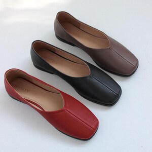 May include: Three pairs of women's flats in black, brown, and red. The shoes have a square toe and a low heel. The brand name "Eternity" is visible on the insole of each shoe.