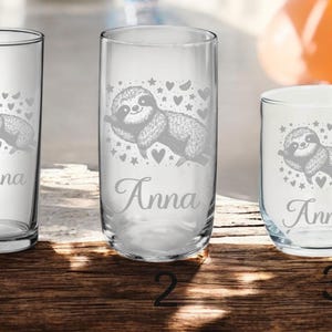 Könnte beinhalten: Drei klare Glasbecher mit einem Faultier-Design und dem Namen "Anna" auf jedem graviert. Das Faultier hält sich an einem Ast fest, mit Sternen und Herzen drumherum.