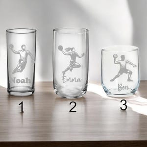 Könnte beinhalten: Drei klare Glasbecher mit personalisierten Namen und einer Grafik einer Person, die Handball spielt. Die Becher sind mit 1, 2 und 3 nummeriert.