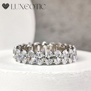 以下が含まれることがあります： 連続したラインにセットされた、楕円形のダイヤモンドが並んだシルバーのバンドリングです。