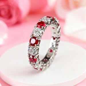Anello eternity classico in argento con rubini simulati e moissanite da 4 mm, perfetto per anniversari di matrimonio.