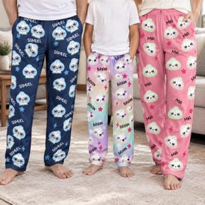 May include: Three pairs of pajama pants featuring a repeating pattern of cartoon dumplings with faces. The left pair is navy blue with the name Samuel, the center pair is a pastel gradient with the name Brian, and the right pair is pink with the name Mia.