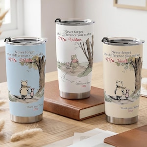 May include: Three stainless steel travel mugs with lids, each featuring a Winnie the Pooh design. The mugs have different background colours: light blue, white, and beige. Each mug has a personalized message and the year 2026.