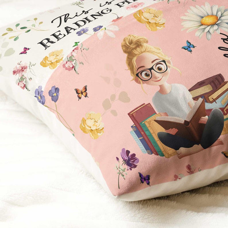 May include: A decorative pillow with a pink and white floral design. The pillow features an illustration of a person reading books, wearing glasses. The text "This is READING PLACE" is printed on the pillow.