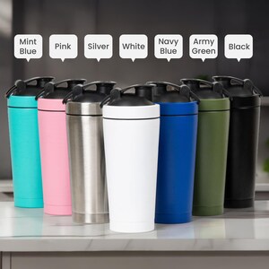 Puede incluir: Una colecci&oacute;n de botellas de agua aisladas en varios colores, incluyendo azul menta, rosa, plateado, blanco, azul marino, verde militar y negro. Cada botella tiene una tapa negra y un dise&ntilde;o cil&iacute;ndrico elegante.