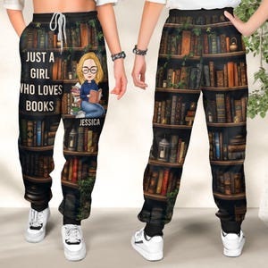 May include: Black sweatpants with a bookshelf print featuring a cartoon girl reading a book. The text "Just a girl who loves books" is printed on the left leg. The name "Jessica" is printed on the right leg.