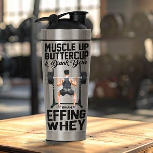 Puede incluir: Una botella mezcladora de acero inoxidable con tapa negra. La botella presenta el texto "MUSCLE UP BUTTERCUP & Drink Your" y "EFFING WHEY". Un gr&aacute;fico de un levantador de pesas tambi&eacute;n est&aacute; en la botella. El nombre "BRIAN" est&aacute; impreso debajo.