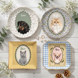 May include: Four decorative plates featuring custom pet portraits. Two round plates show a black and tan dachshund labeled Timber and a fluffy ginger cat labeled Butter. Two square plates show a grey cat labeled Olive and a chihuahua labeled Momo.