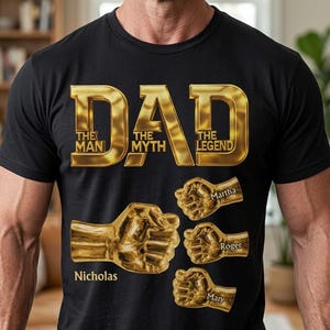 May include: A black short-sleeved t-shirt featuring gold metallic-style text that reads DAD THE MAN THE MYTH THE LEGEND. Below the text are four gold fist graphics, each labeled with the names Nicholas, Martha, Roger, and Mary in gold font.