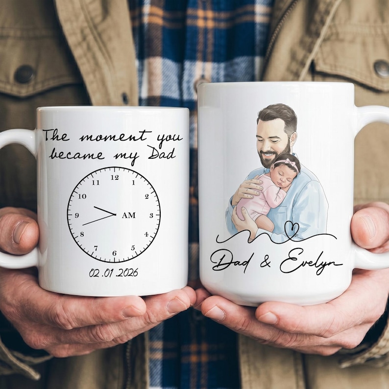 Pode incluir: Duas canecas de cer&acirc;mica brancas. Uma caneca apresenta um design de rel&oacute;gio com o texto "The moment you became my Dad" e a data 02.01.2026. A outra caneca tem uma ilustra&ccedil;&atilde;o de um pai segurando um beb&ecirc;, com o texto "Dad & Evelyn".