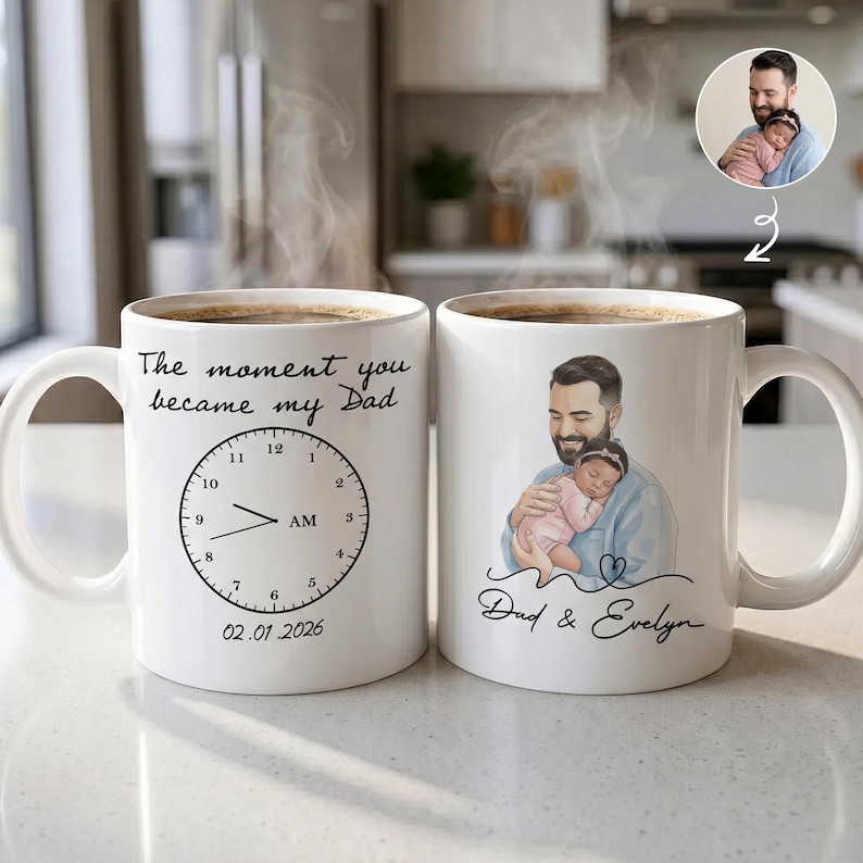 Pode incluir: Duas canecas de cer&acirc;mica branca com caf&eacute;. Uma caneca tem o texto "The moment you became my Dad" com um design de rel&oacute;gio e a data 02.01.2026. A outra caneca tem uma ilustra&ccedil;&atilde;o de um pai segurando um beb&ecirc; e o texto "Dad & Evelyn."