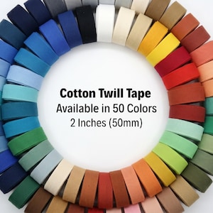 May include: A circular arrangement of cotton twill tape in a spectrum of colors. The image displays rolls of tape in various shades, including blues, greens, yellows, reds, and browns. Text on the image reads "Cotton Twill Tape Available in 50 Colors 2 Inches (50mm)".