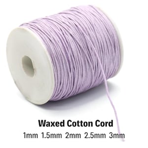 May include: A spool of lavender waxed cotton cord. The cord is wrapped around a white cardboard spool. Text on the image reads "Waxed Cotton Cord" and lists cord sizes: 1mm, 1.5mm, 2mm, 2.5mm, and 3mm. The cord is unwound slightly from the spool.