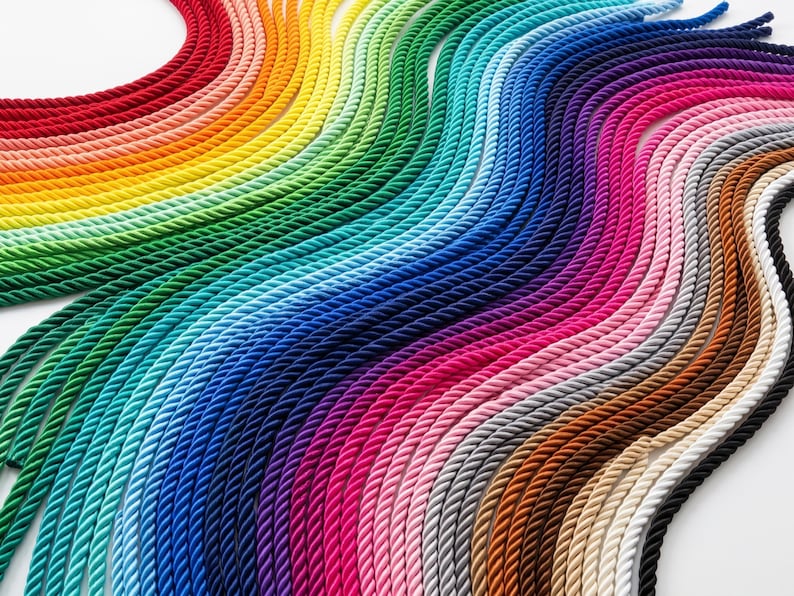 May include: A vibrant display of colorful ropes arranged in a wave pattern. The ropes span a spectrum of hues, from red to violet, creating a visually appealing gradient. The ropes are tightly twisted, suggesting durability and a variety of potential uses.
