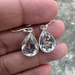 May include: A pair of silver teardrop earrings with clear quartz stones.