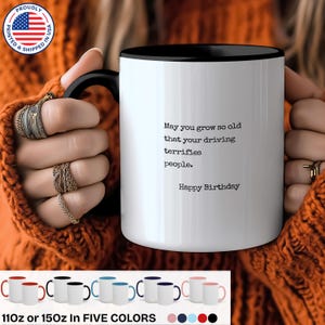 May include: White ceramic mug with a black rim and handle. The mug has a funny birthday message that reads "May you grow so old that your driving terrifies people. Happy Birthday".
