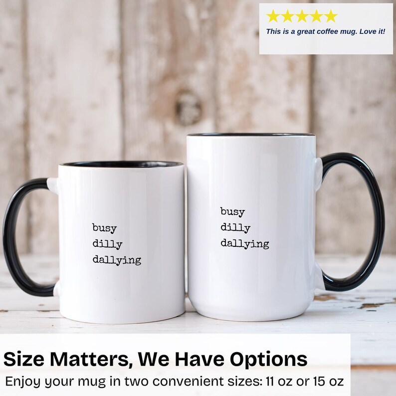 May include: Two white coffee mugs with black handles and black rims. The mugs have the text "busy dilly dallying" printed in black on the front. The mugs are available in two sizes: 11 oz or 15 oz.