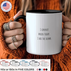 Może przedstawiać: Biały ceramiczny kubek z czarnym wnętrzem i uchwytem. Kubek zawiera napis "I CANNOT BRAIN TODAY. I HAS THE DUMB." Dostępny w pięciu kolorach, dumnie drukowany i wysyłany w USA.