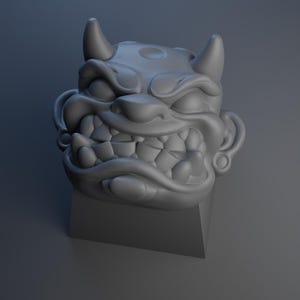 May include: A gray 3D printed keycap featuring a detailed oni mask with horns, a wide open mouth, and sharp teeth.