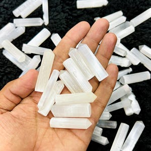 Può includere: Una collezione di punte di cristallo di selenite bianca, nota anche come spato satinato, in varie dimensioni e forme. I cristalli sono lisci e hanno un aspetto setoso e traslucido.