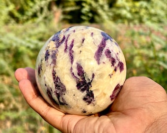 May include: A white and purple amethyst sphere with a swirling pattern. The sphere is smooth and polished.