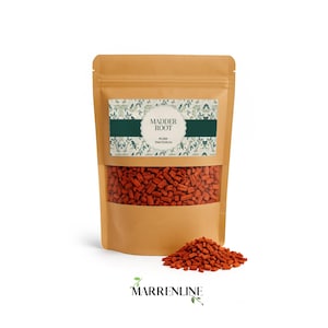 Peut inclure: Un sachet debout beige contenant de petits morceaux irréguliers de racine de garance séchée. L'étiquette présente un motif botanique, une bande horizontale vert foncé et le texte MADDER ROOT RUBIA TINCTORUM. Un tas de racine est devant.