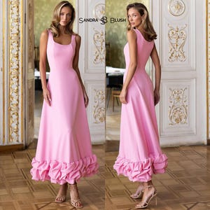 May include: A sleeveless, floor-length pink dress with a square neckline and a ruffled hem. The dress is shown in two views, with the text "SANDRA BLUSH" visible. The model wears strappy heels. The dress is suitable for formal occasions.