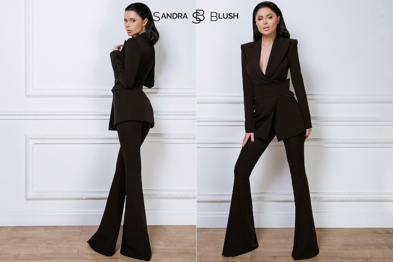 May include: A brown pantsuit with a blazer and flared pants. The blazer has a deep V-neck and a single button closure. The pants have a wide leg and a high waist. The model is wearing the pantsuit with a neutral expression.