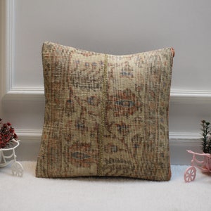 Peut inclure: Un coussin beige et brun à motifs avec une bordure à franges. Le coussin est fait d'un tissu tissé et présente un motif floral subtil.