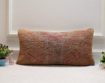 May include: A rectangular brown and pink patterned throw pillow with a woven texture.