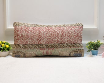 May include: A rectangular cushion with a pink and brown patterned fabric. The cushion is made of a woven fabric with a geometric design.
