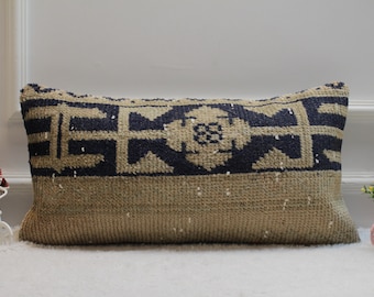 May include: A beige and navy blue patterned cushion with a geometric design. The cushion is made of a woven fabric and has a rectangular shape.