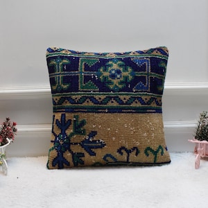 May include: A decorative cushion with a blue, green and beige geometric pattern. The cushion is made from a soft, woven fabric and has a subtle sheen.
