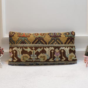 May include: A rectangular pillow with a brown, yellow, and blue geometric pattern. The pillow is made of woven fabric and has a fringe border.
