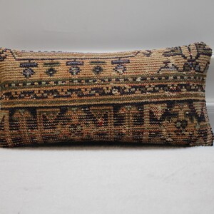 Peut inclure: Un coussin rectangulaire en tissu à motifs marrons, verts et bleus. Le coussin présente un design traditionnel avec des formes géométriques et des motifs floraux.